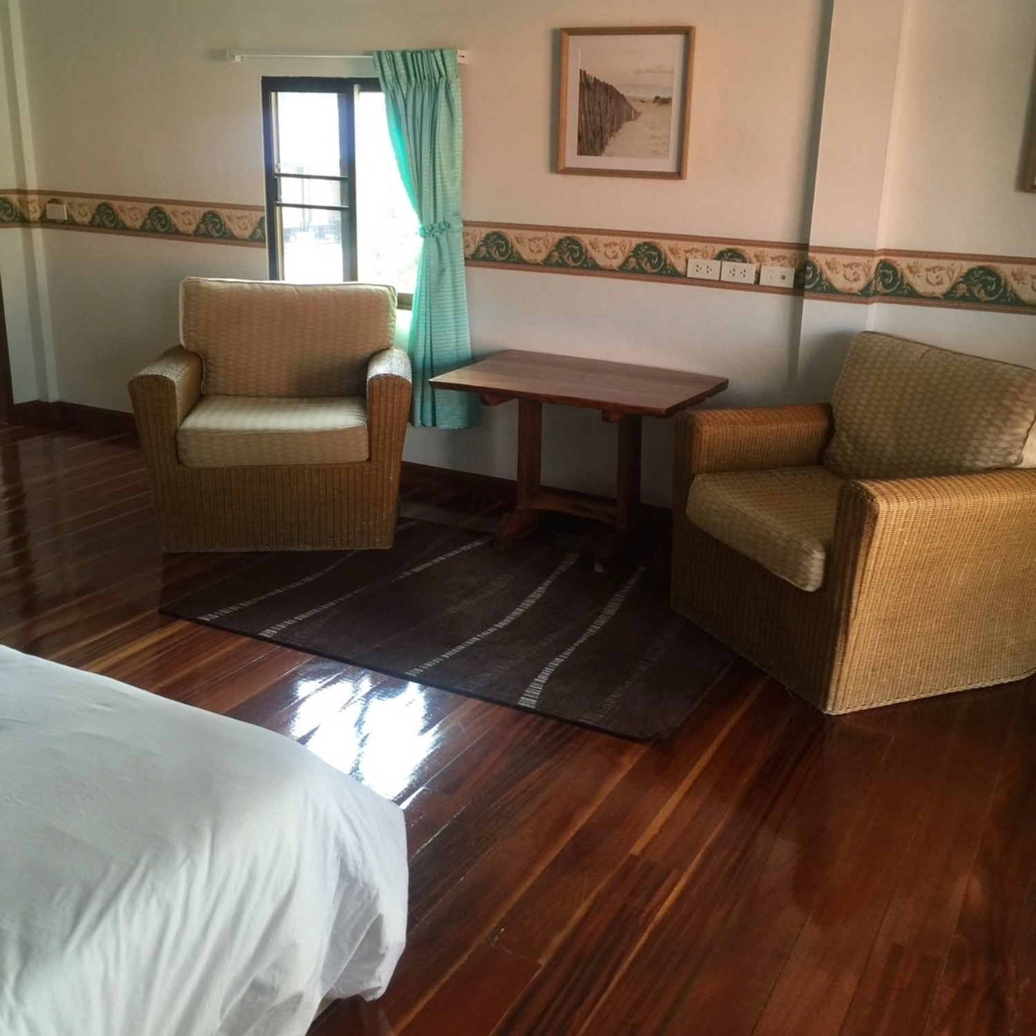 A seating area in the Superior Room at Lyndale Lodge with two rattan armchairs and a wooden table beside a bright window
